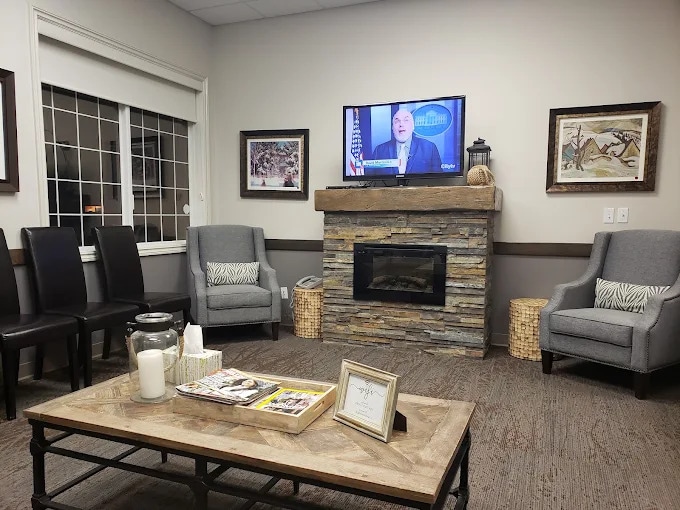 Waiting lounge at High River Dental Centre with armchairs, a fireplace and a television